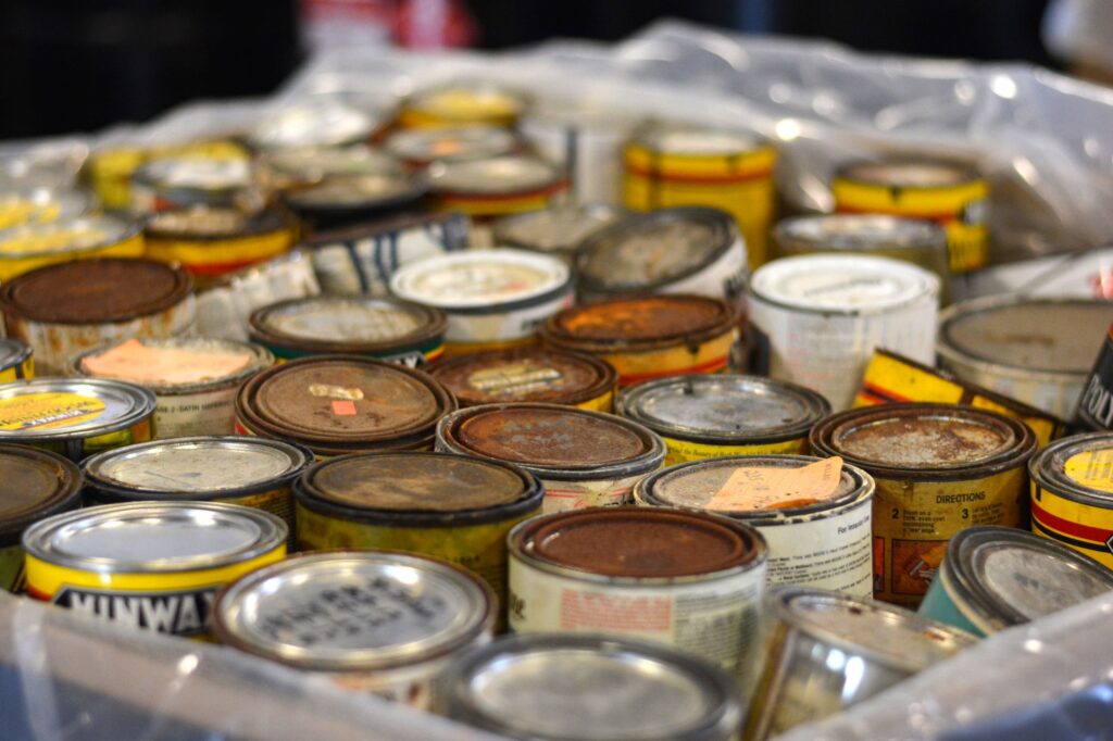 Collection of paint and stain cans stored for disposal in an NEDT bin.