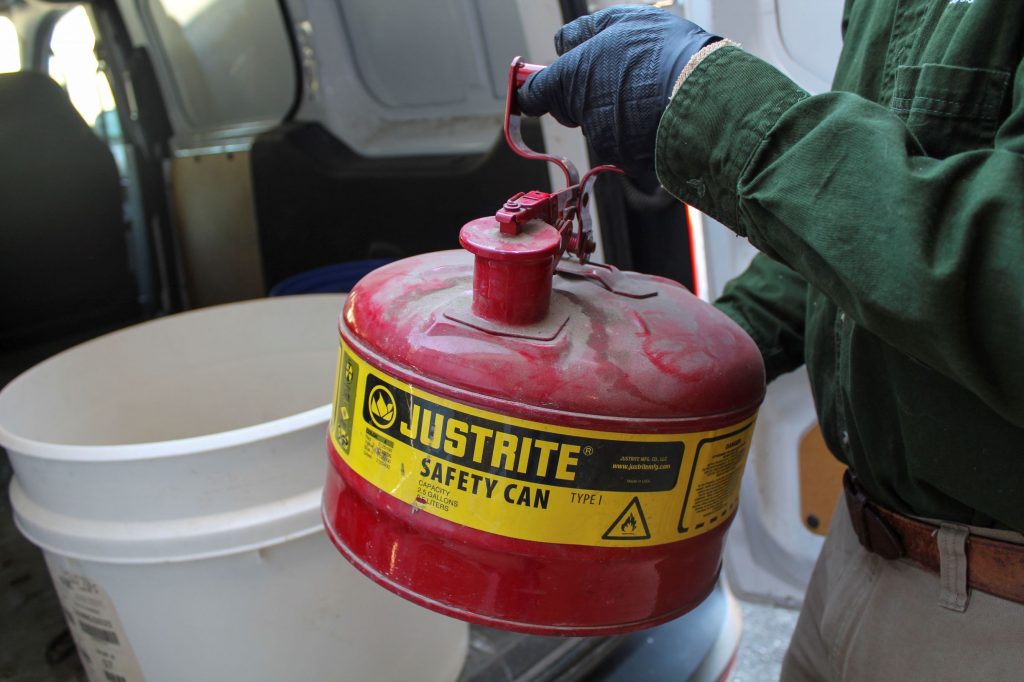 NEDT technician transports a can of gasoline to a van for disposal.