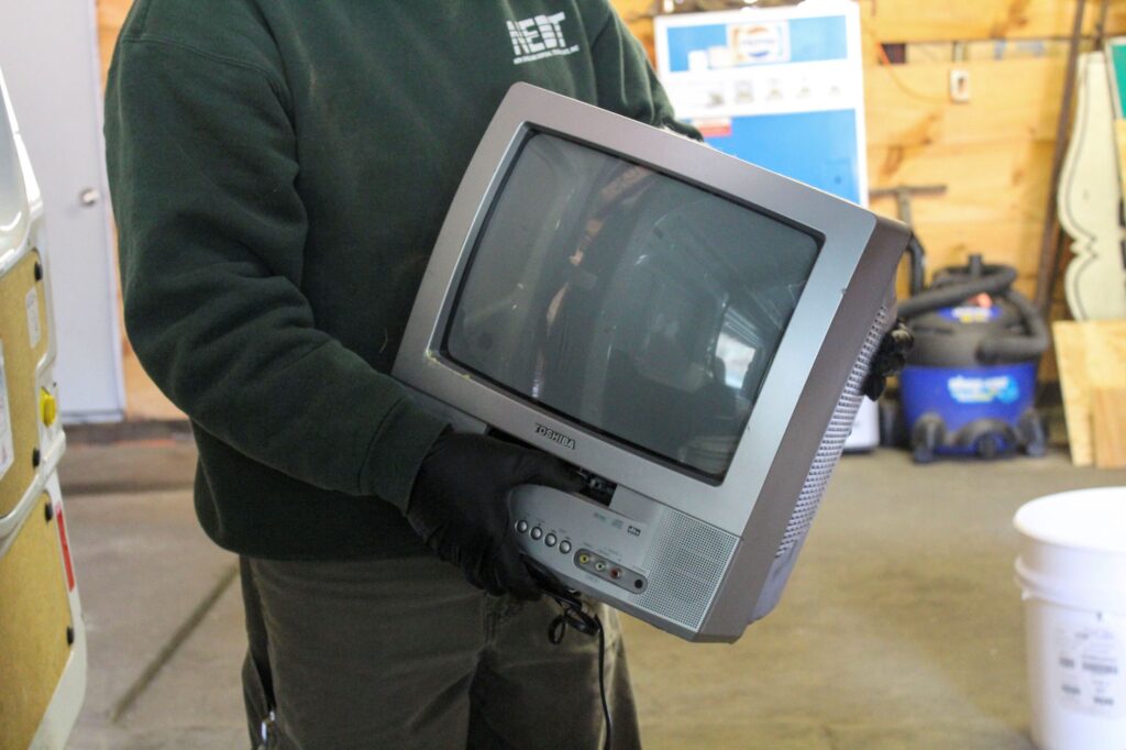 NEDT technician holds a Cathode Ray Tube (CRT) TV.