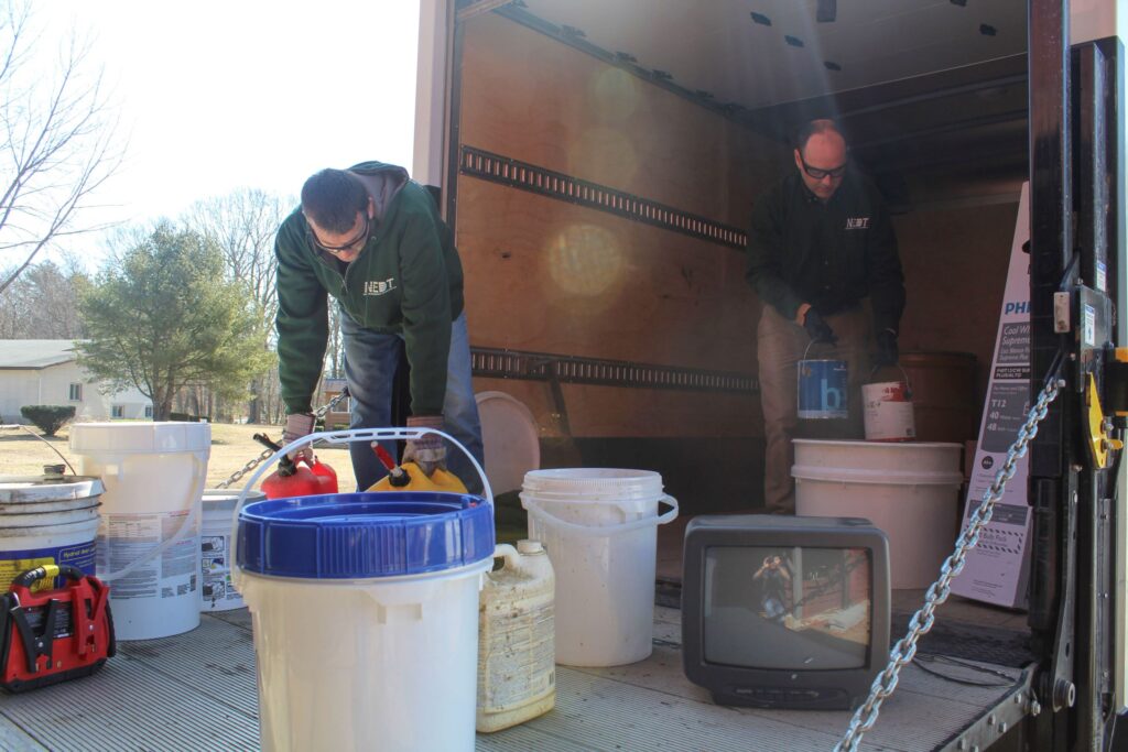 NEDT technicians load household hazardous waste into a truck from an estate.