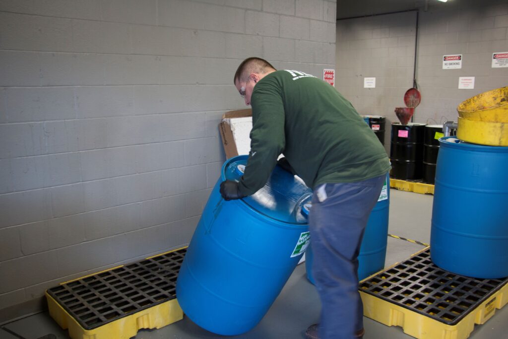An NEDT technician handles a household hazardous waste container.
