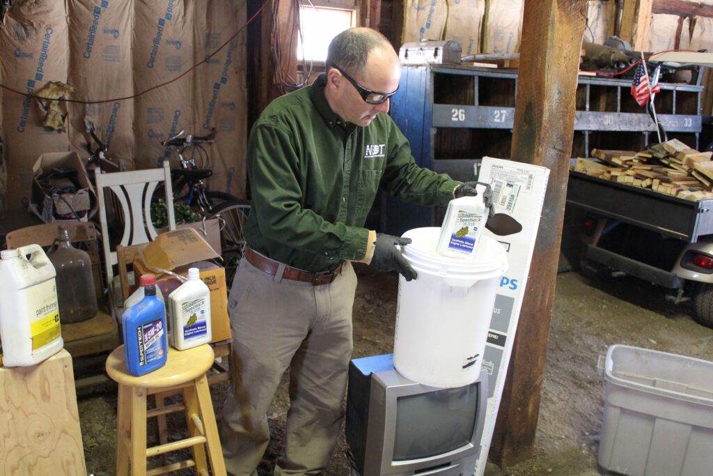 NEDT Technician gathering household hazardous waste from a garage.