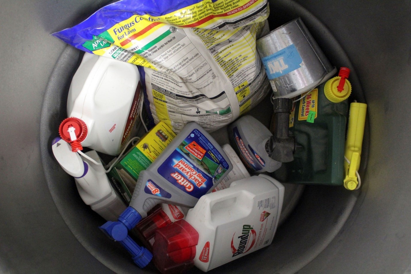 A large bucket filled with bottles of pesticides and herbicides