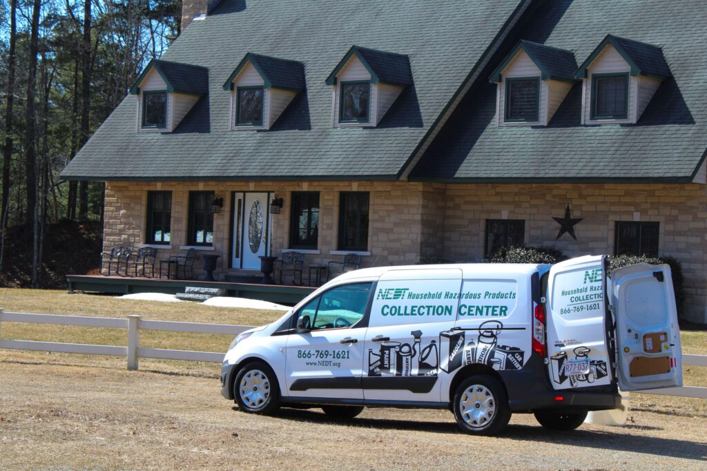 NEDT Pick Up Service van parked in front of a home with back doors open.