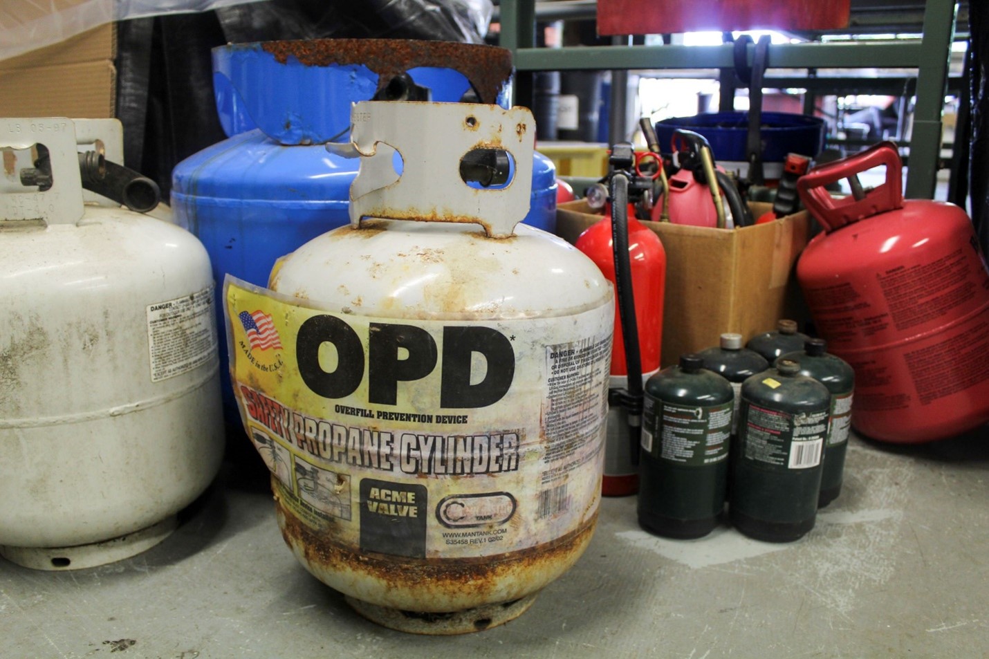An assortment of propane tanks, both large and small, on a cement floor