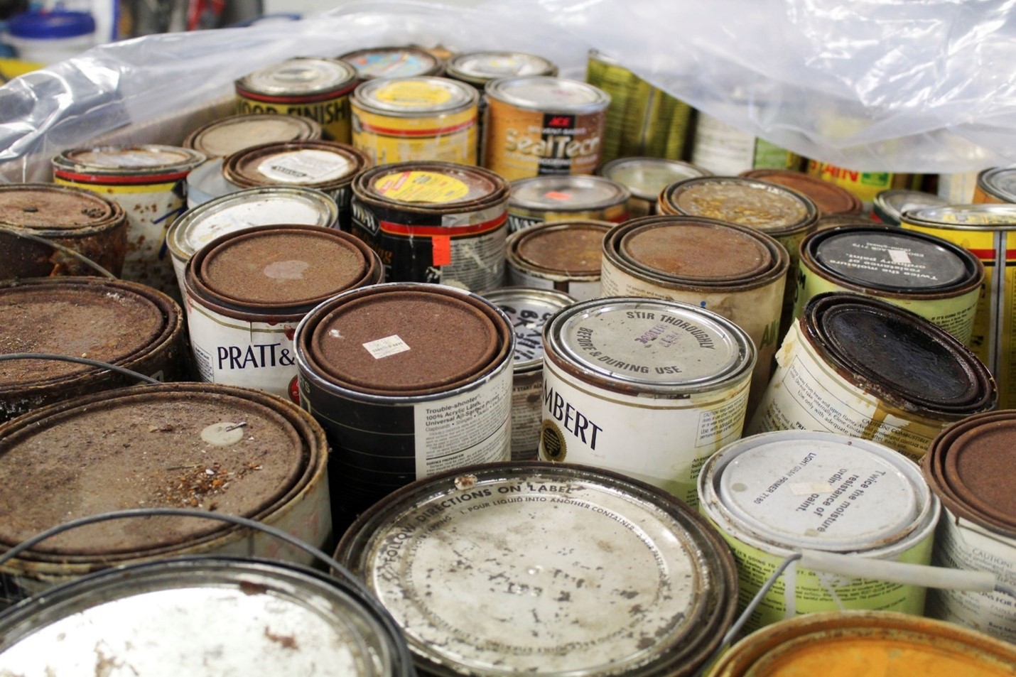A closeup image of several rusted cans of paint and stains