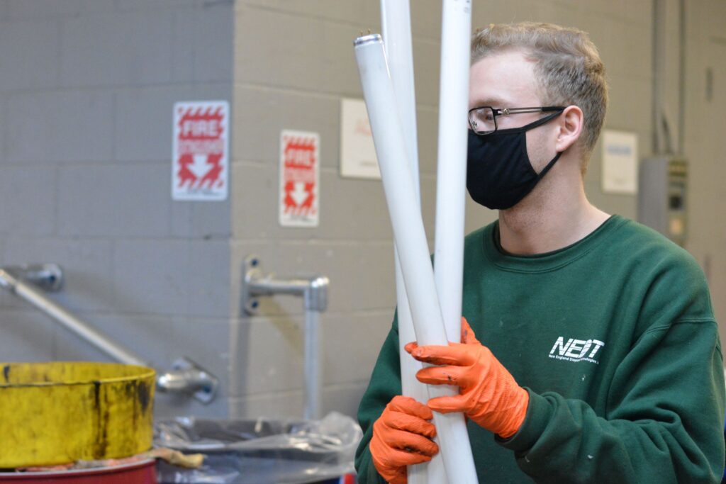 NEDT Technician holding several fluorescent lighting tubes.