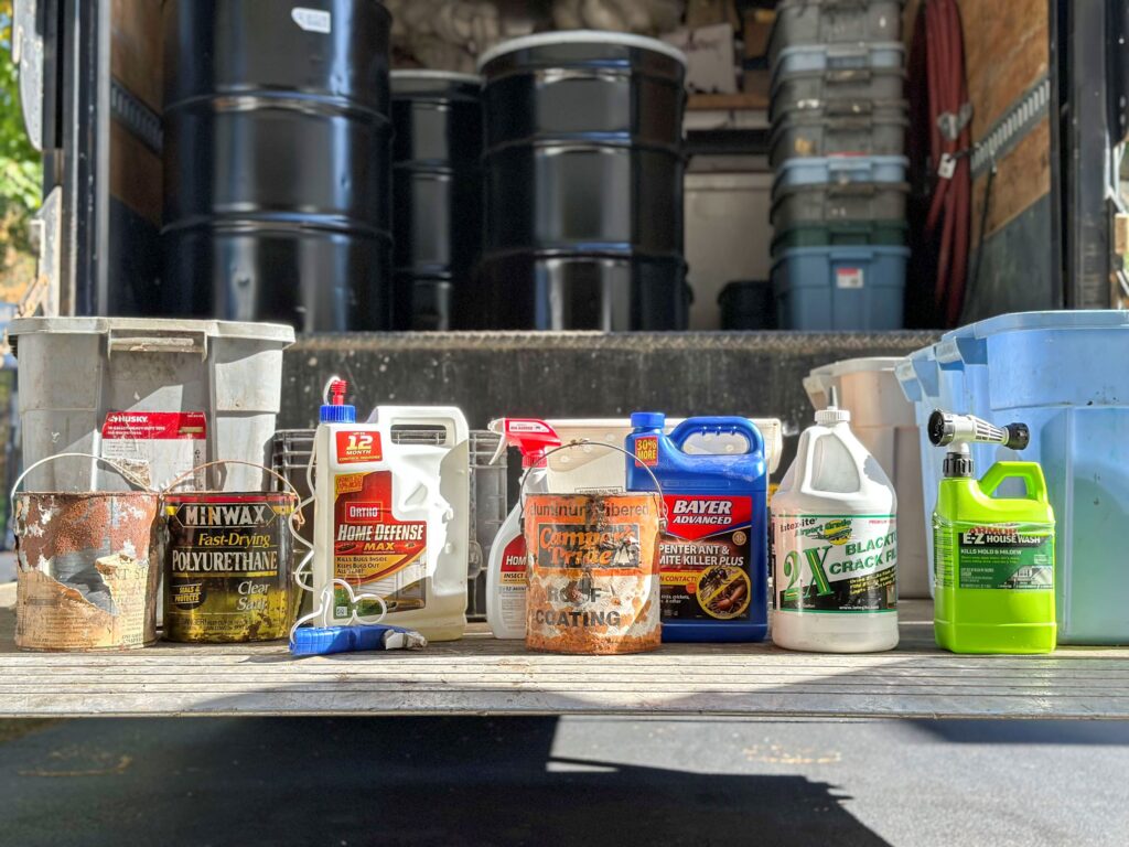 Various household hazardous products arrayed in front of an NEDT transport truck.