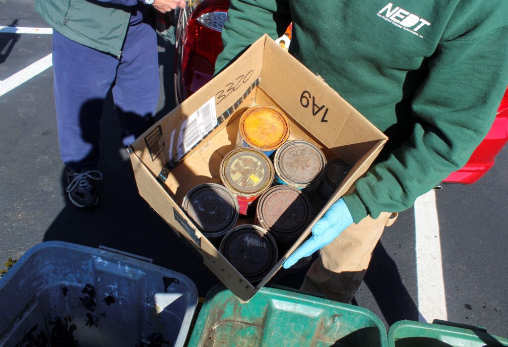 NEDT Technicians handling rusting metal containers at an NEDT Collection Center.