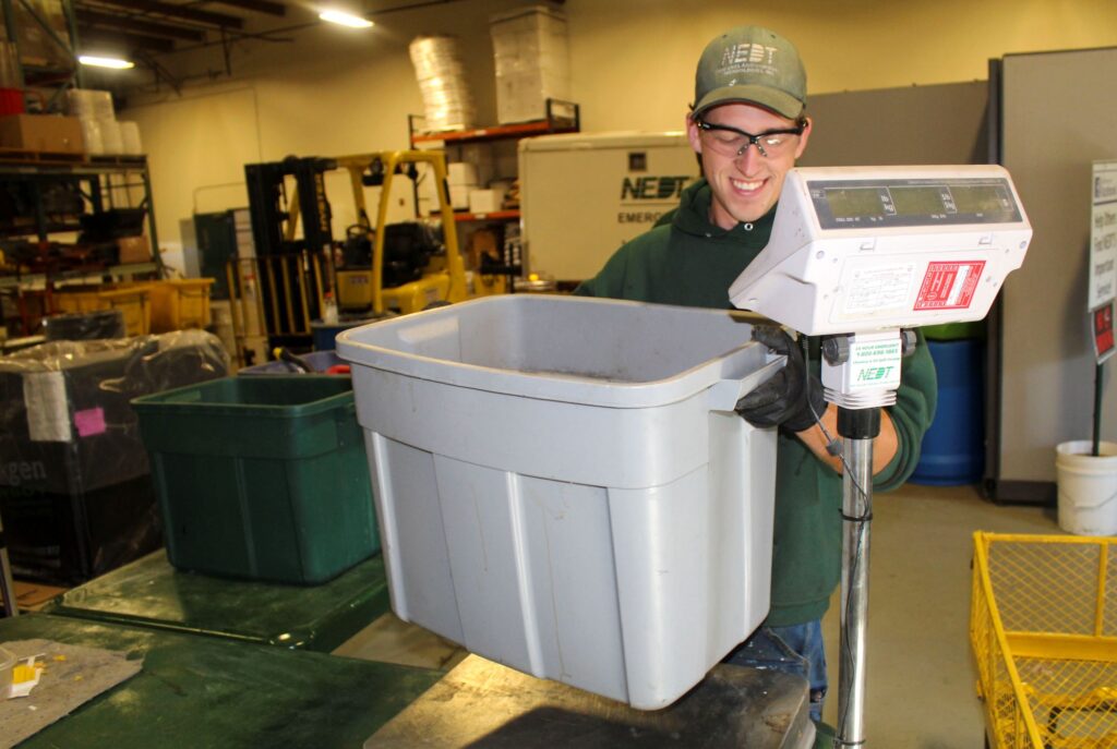 NEDT Technician weighing hazardous waste prior to disposal.