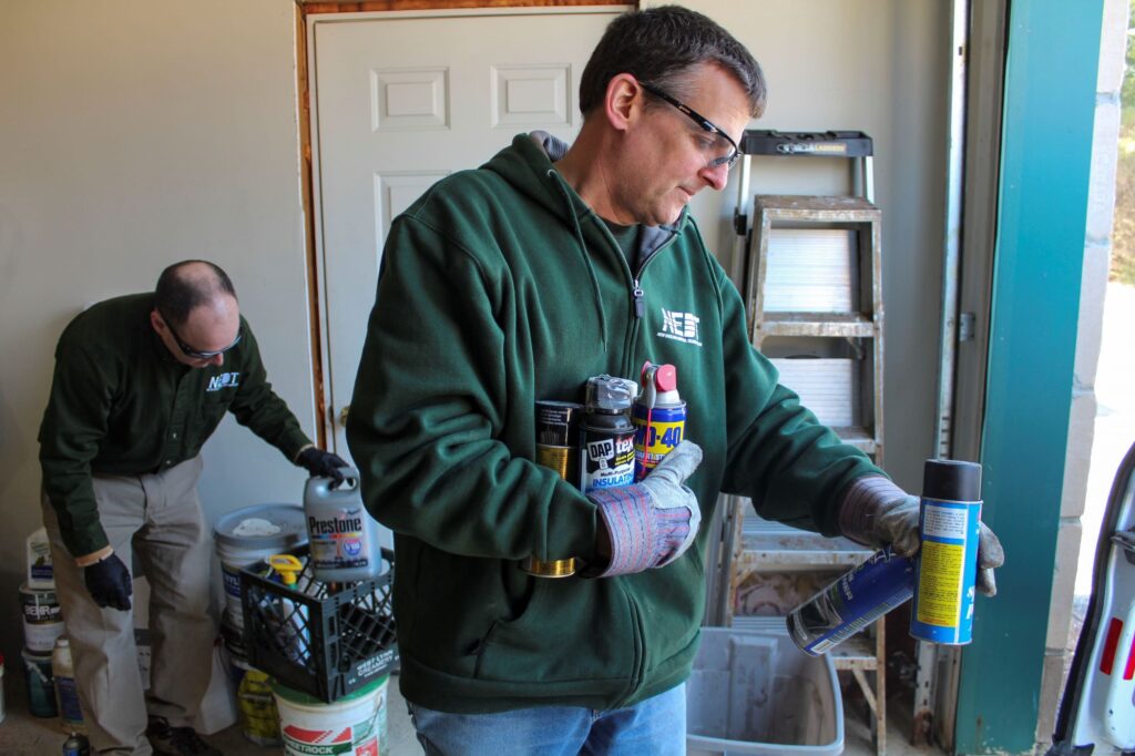 Two NEDT Staff emptying household hazardous waste from a home's garage.