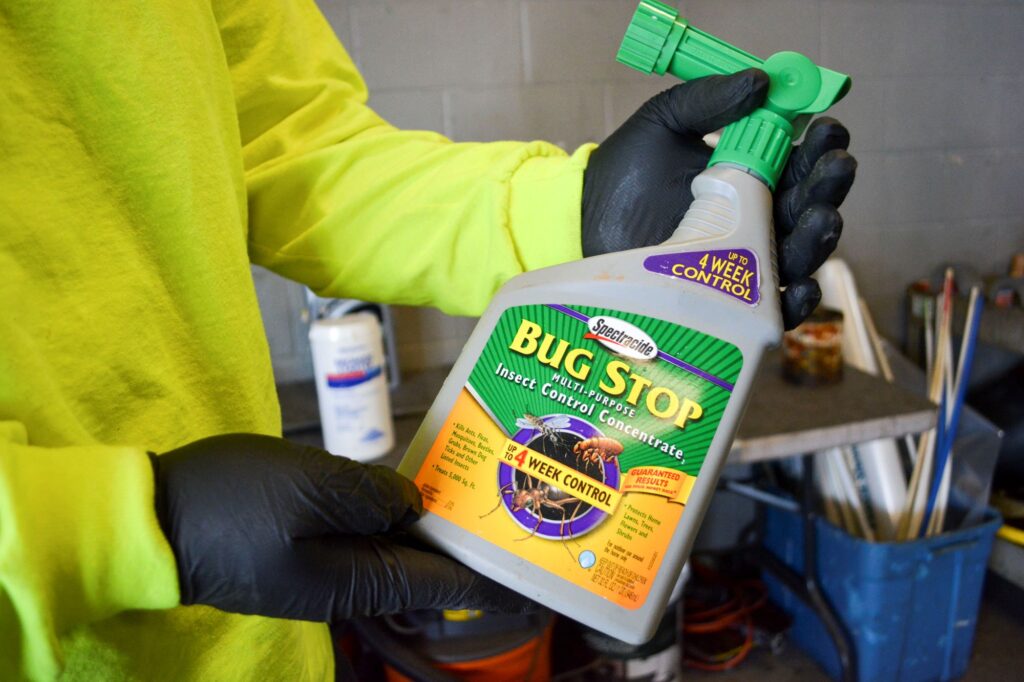 NEDT technician holding Bug Stop insecticide as an example of gardening pesticides.