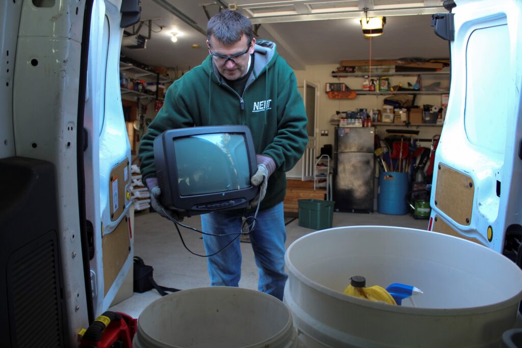 NEDT staff removing household hazardous products from a garage into a van.