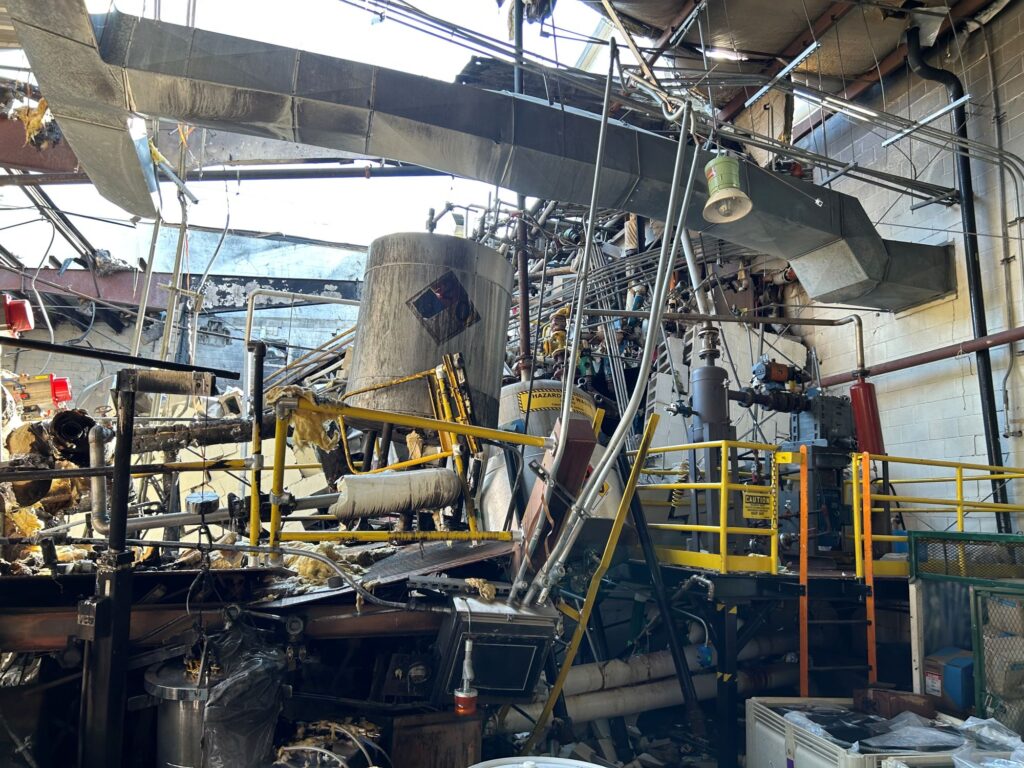Interior of the chemical plant after the explosion. The roof is mostly gone, and debris and chemical spills litter the floor.