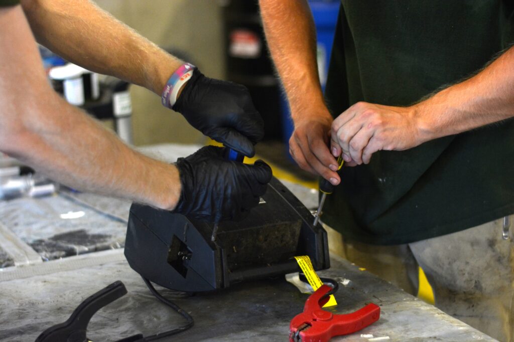 Two NEDT technicians disassemble eWaste at a collection center.