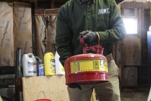 NEDT Technician removing a metal gasoline container from a home for disposal.