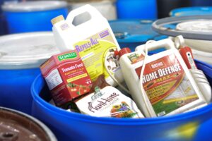 Various types of gardening hazardous waste in a disposal drum.