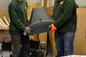 Two NEDT staffers handle a large CRT TV at an NEDT Collection Center.