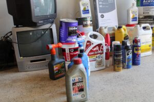 A large amount of household hazardous waste piled up in a garage awaiting disposal.